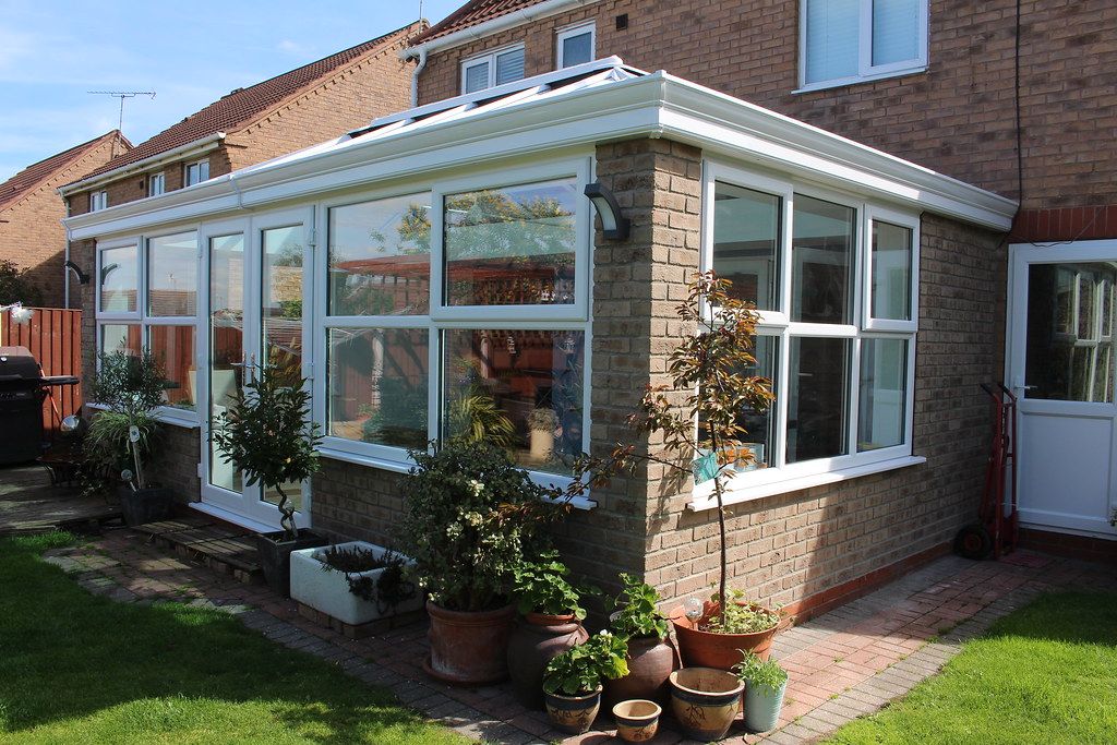 A white Victorian style conservatory attached to a brick house