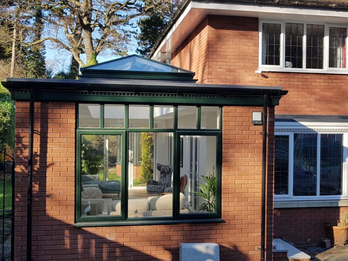 Orangery with a roof lantern and dark grey frames on a red brick house