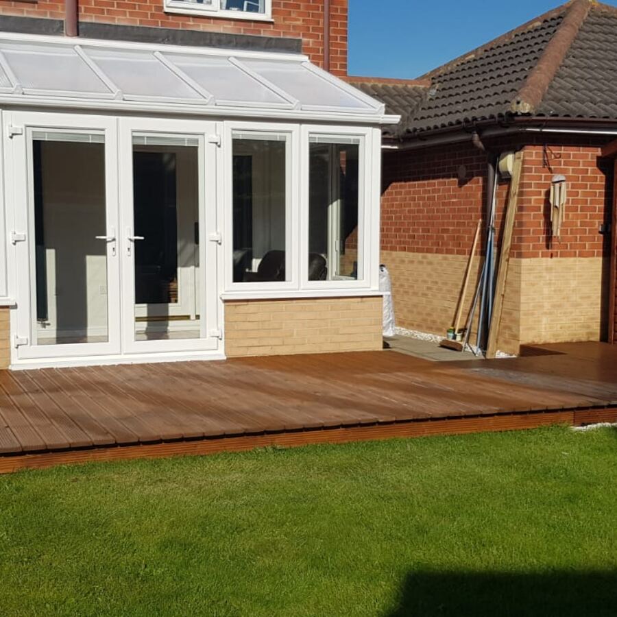 White lean-to conservatory with French doors onto a timber deck